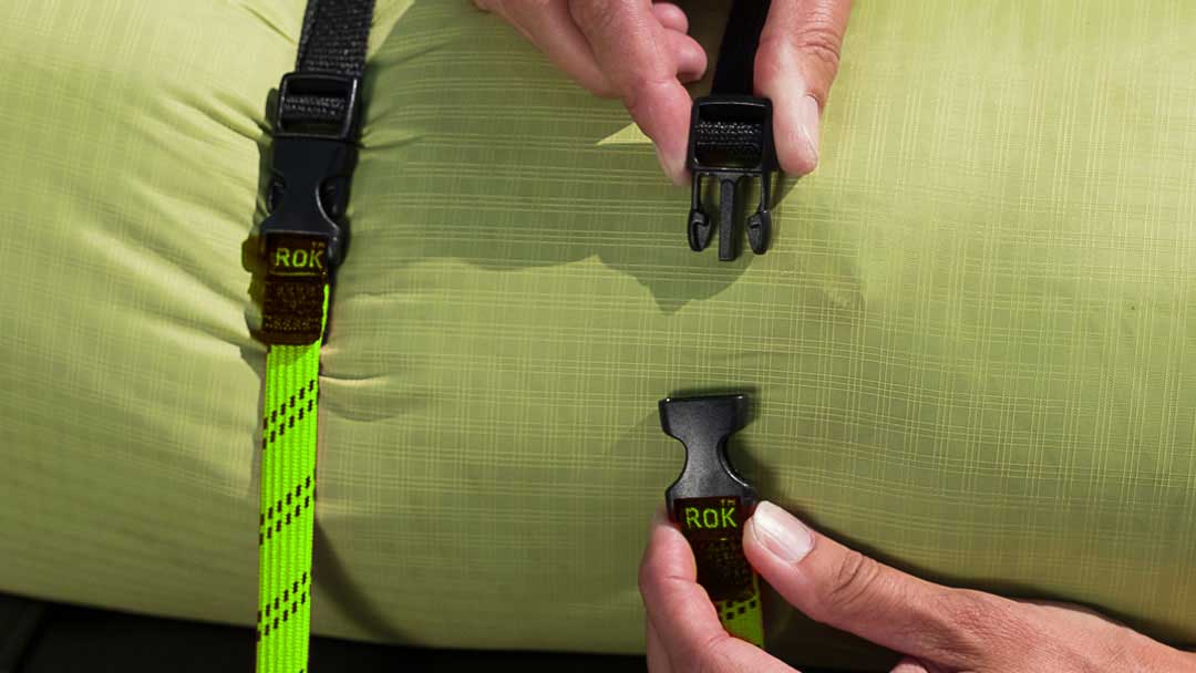 Person securing luggage with ROKStraps quick-release buckle strap, showing durable, flat strap keeping cargo safe on a bike or motorcycle